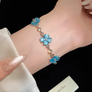 Primo piano dettagliato di un elegante bracciale a fiori in pietra occhio di gatto blu al polso
