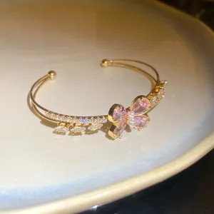Detailed macro shot of an elegant gold double-layer cuff bracelet with pink zircon butterfly