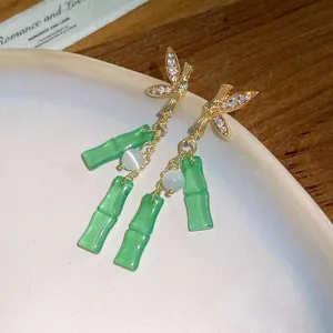 Dettaglio ravvicinato di orecchini a forma di bambù con pendenti in resina verde.