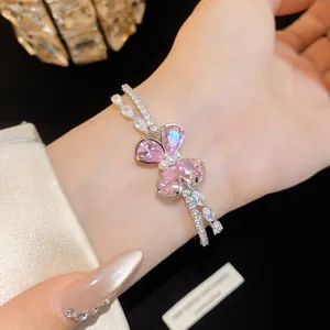 Close-up of an elegant double-layer silver bracelet with a pink zircon butterfly on a wrist.