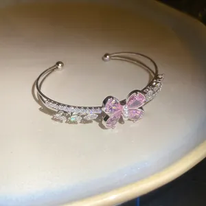 Macro detail of elegant pink zircon butterfly and pearl inlay on a double open bangle