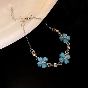 Dettaglio di un braccialetto con fiori in pietra occhio di gatto blu e strass brillanti.