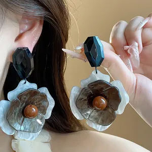 Primer plano de grandes pendientes de flores de acrílico con gemas negras geométricas