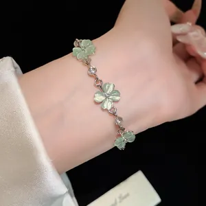Dettaglio di un elegante bracciale a fiori verdi con pietre occhio di gatto sul polso.