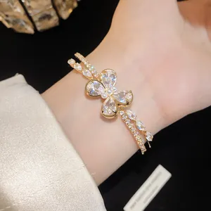 Macro detail view of a luxury gold double-layer open bracelet with sparkling zircon butterfly