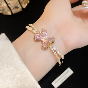 Detail view of a gold double-layer bangle featuring a pink zircon butterfly and pearls.