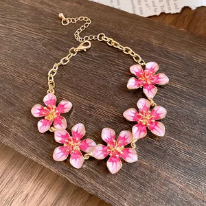 Dettaglio dei fiori in smalto rosa su un bracciale in metallo dorato vintage