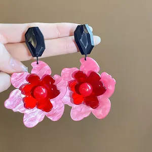Detalle macro de pendientes de botón de flores acrílicas retro con pétalos en rosa y rojo