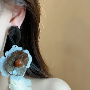 Primer plano de pendientes de flores de acrílico vintage con tuerca geométrica negra