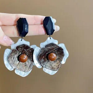 Primer plano de aretes de flores acrílicos retro de gran tamaño con pétalos rugosos.