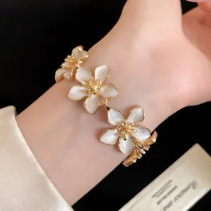 Primo piano dettagliato di un bracciale a fiori vintage con petali in smalto bianco e finitura oro