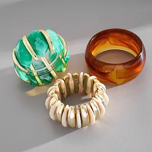 Dettaglio di braccialetti geometrici retrò in marmo acrilico verde e ambra.