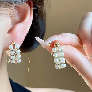 Elegant French vintage style pearl and zircon stud earrings shown on model's ear and hand