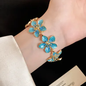 Primo piano di un braccialetto vintage a fiori in smalto blu indossato sul polso
