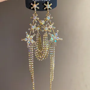 Detailed macro of gold-toned rhinestone earrings with snowflake motifs and long tassels
