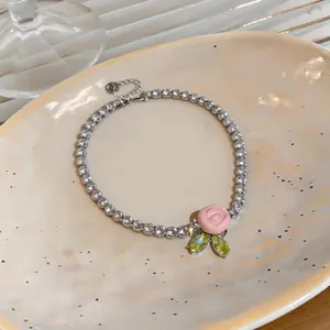 Dettaglio di una collana in zircone argento con una rosa in resina rosa e foglie.