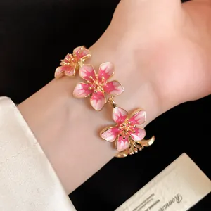 Vista macro dettagliata dei ciondoli a fiore in smalto rosa di questo bracciale retrò