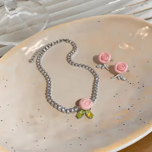 Vista dettagliata del set di gioielli con rose in resina rosa, collana e orecchini.