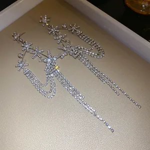 Close-up of elegant silver needle earrings with rhinestone flowers and long tassels