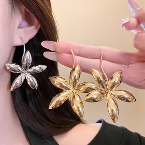 Makroansicht von übergroßen Metallblumen-Ohrringen in Gold und Silber