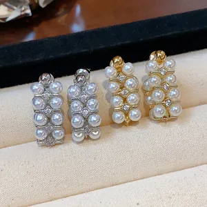 Close-up of French vintage pearl earrings with zircon accents in gold and silver finishes.