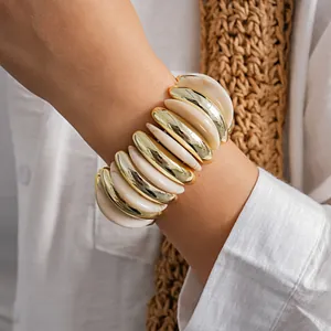 Primo piano di un bracciale elastico geometrico in acrilico marmorizzato e oro lucido