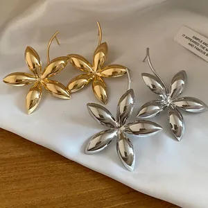 Detaillierte Makroansicht von glänzenden gold- und silberfarbenen Blumenohrringen auf Seide.