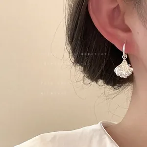 Primo piano dettagliato di un orecchino a forma di conchiglia in argento su una modella