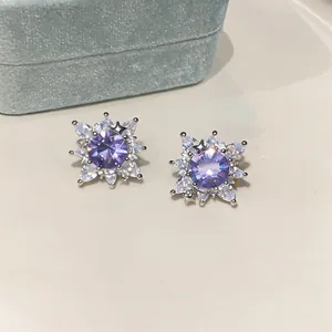 Detailed macro shot of sparkling flower-shaped earrings with purple center stones.