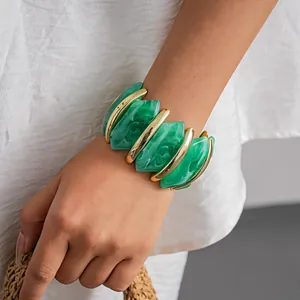 Primo piano di un bracciale geometrico in acrilico marmorizzato verde con accenti dorati