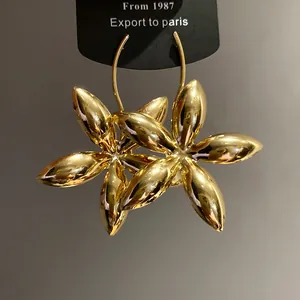 Detailansicht der glänzenden goldenen Blumenohrringe mit poliertem Metallic-Finish.