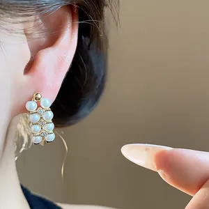 Detail shot of French vintage style earrings with pearls and zircons worn on ear