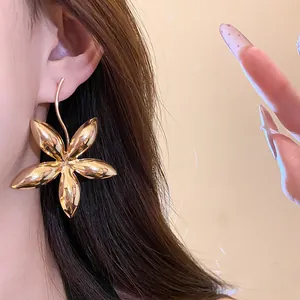 Elegante große goldene Blumen-Ohrhänger an einem Modell für einen schicken Look.