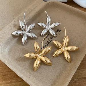 Details von gold- und silberfarbenen Blütenohrringen auf einem Papiertablett