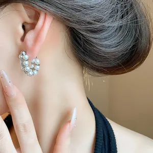 Detailed close-up showing elegant pearl and zircon hoop earrings worn on a female ear