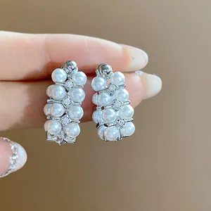 Close-up of elegant French vintage earrings with white pearls and sparkling zircons.