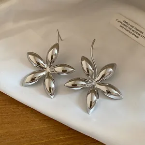 Nahaufnahme glänzender silberner Blumen-Ohrstecker mit edler Metallreflexion.