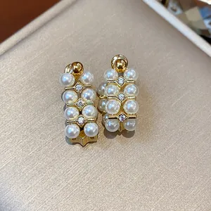 Macro view of French vintage gold-plated stud earrings decorated with pearls and zircons