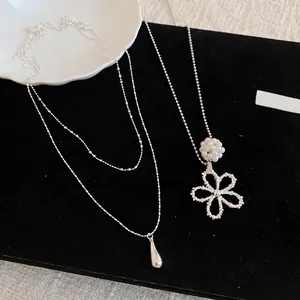 Double-layered silver necklace featuring elegant teardrop and pearl flower pendants