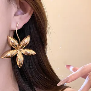 Detaillierte Makroansicht eines großen, glänzenden, goldenen Blumenohrrings an einem Modell