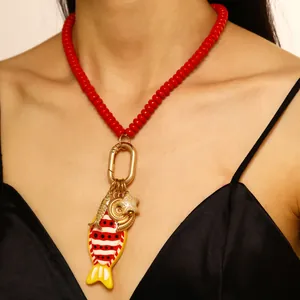 Detalle del collar de cuentas rojas estilo océano con dijes de estrella de mar y concha