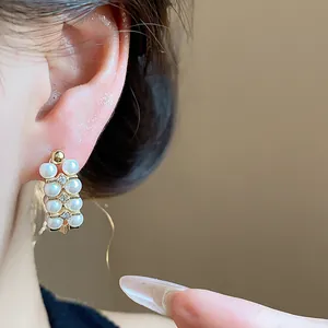 Close-up of pearl and zircon details on a French vintage style gold earring worn on ear