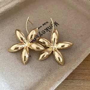 Detaillierte Makroansicht von polierten goldfarbenen Blumenohrringen auf einem Papiertablett