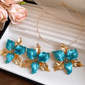 Detailed view of vintage blue enamel flower earrings and matching gold torque necklace.