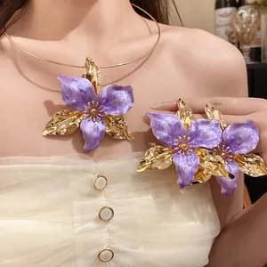 Close-up of vintage purple enamel flower jewelry set with golden petals on model.