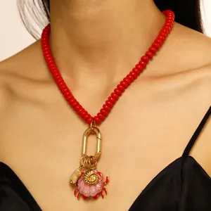 Primer plano de collar de estilo oceánico con cuentas rojas y dije de cangrejo