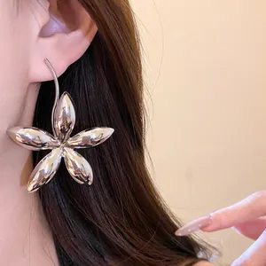 Nahaufnahme eines großen silbernen Blumenohrrings mit polierter Metallic-Oberfläche
