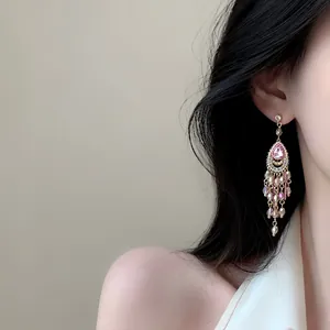 Detail view of elegant palace style chandelier earrings with pink stones and tassels.