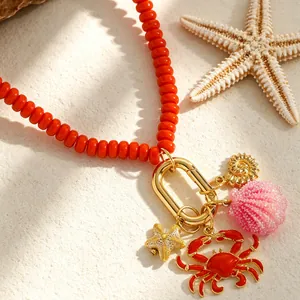 Primer plano de dijes marinos con cangrejo rojo y estrella de mar en collar de cuentas