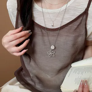 Close-up detail of a silver double-layer necklace with flower and pearl charms.
